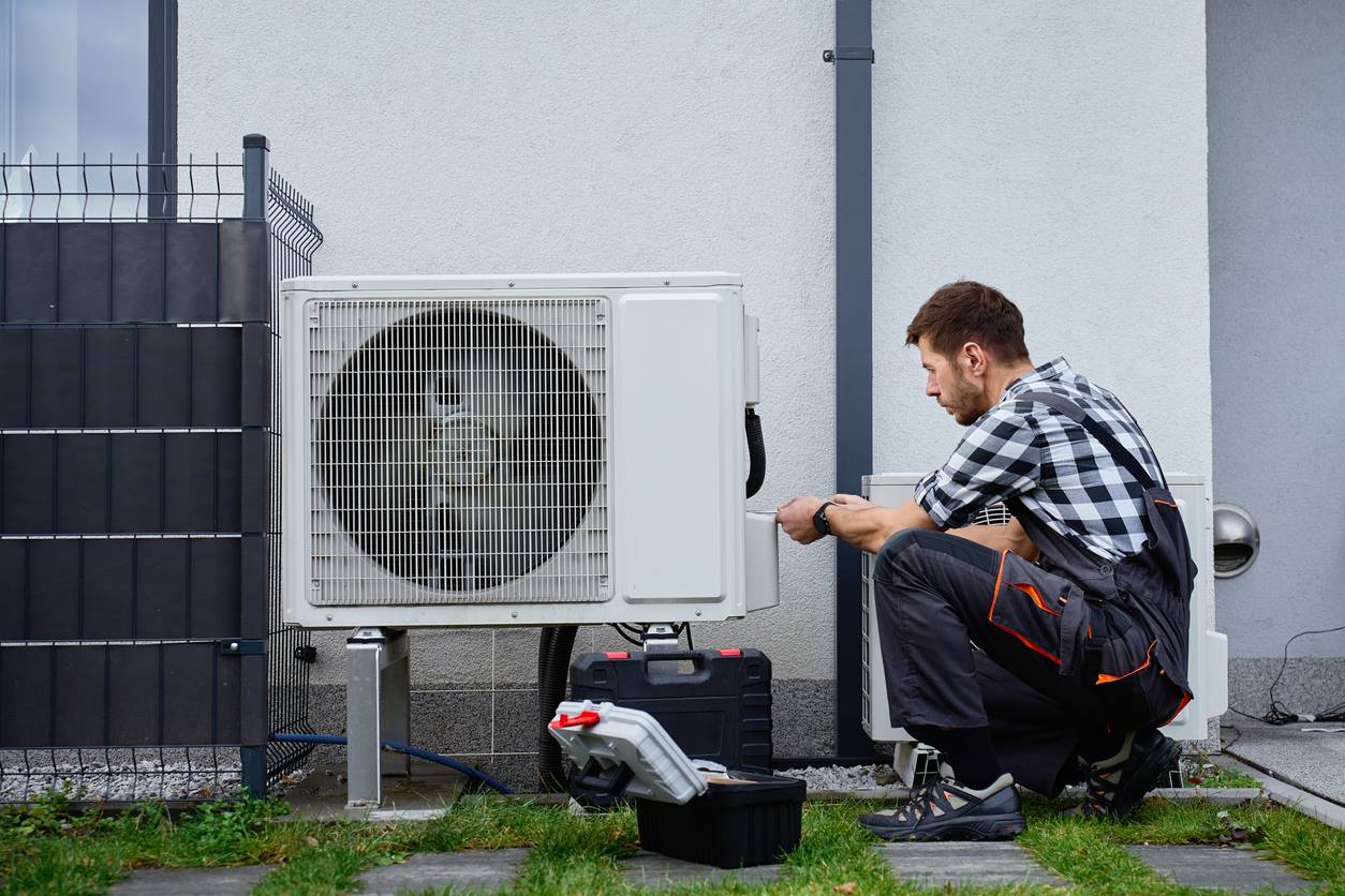 Technician installing a ductless mini-split outdoor unit at a Garden City, NY home