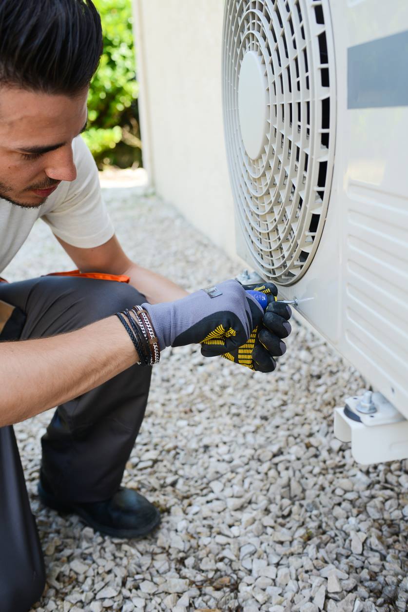 Technician performing heat pump maintenance and tune-up on an outdoor unit